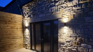 A stone building with a wooden deck and a glass door entrance. - Comfortable, modern cottage that sleeps up to 6. Ideal hub to explore Northumberland! (Morpeth)