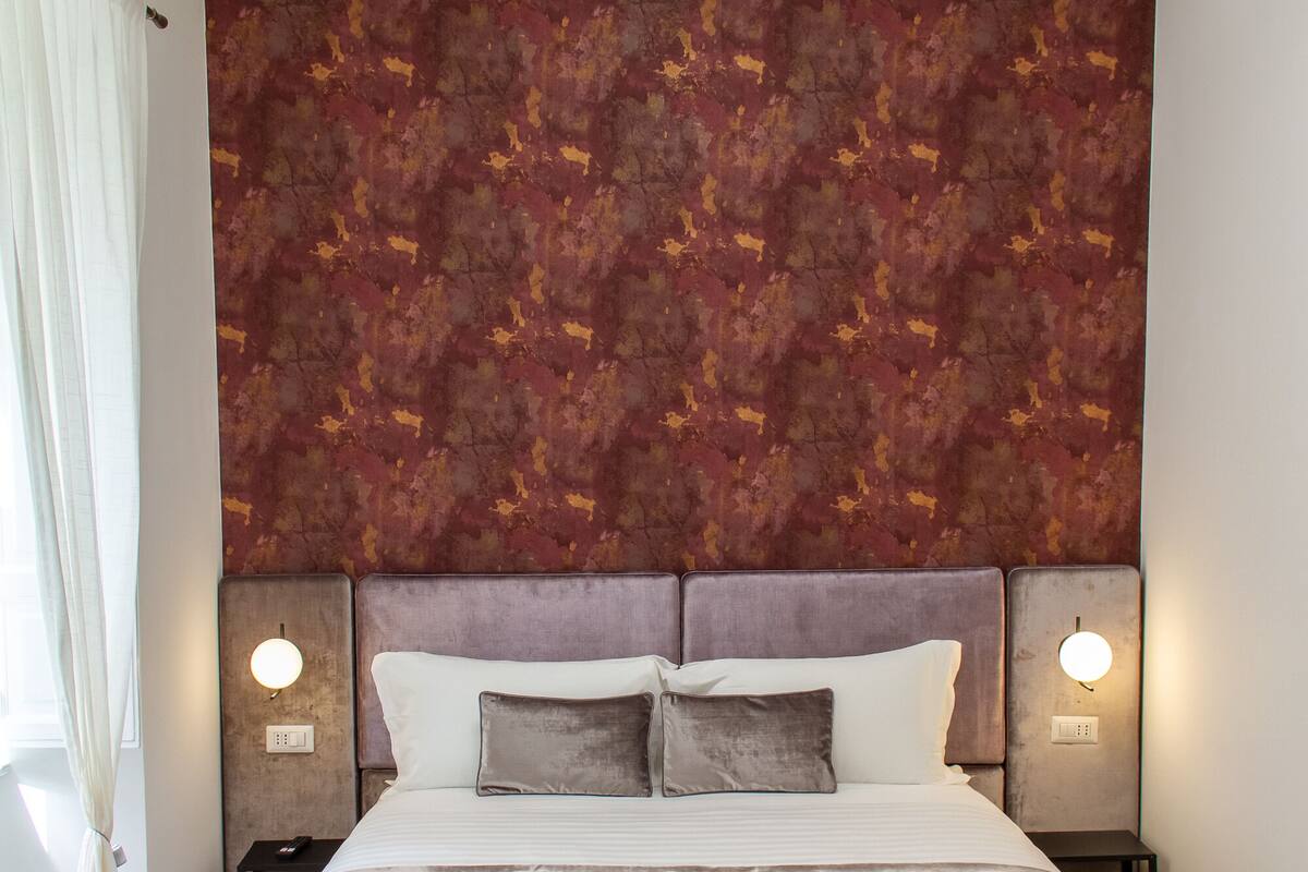 A bedroom with a large bed, two bedside tables, and a wall-mounted TV.