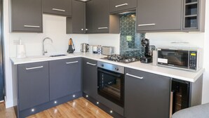 Una cocina moderna con gabinetes gris oscuro, encimera blanca, horno empotrado, microondas y cafetera.
