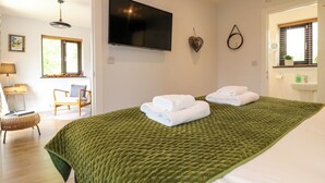 Una habitación con cama, televisión, silla, escritorio y ventana con persianas.