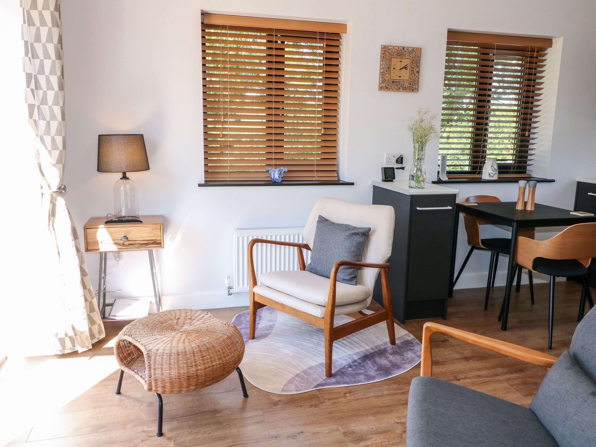 Una sala de estar moderna con un sofá, una mesa de comedor con sillas, una lámpara y un radiador.