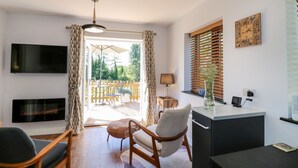 Una sala de estar moderna con un televisor de pantalla plana, una zona de comedor con una mesa y sillas, un sofá y un escritorio con una computadora.