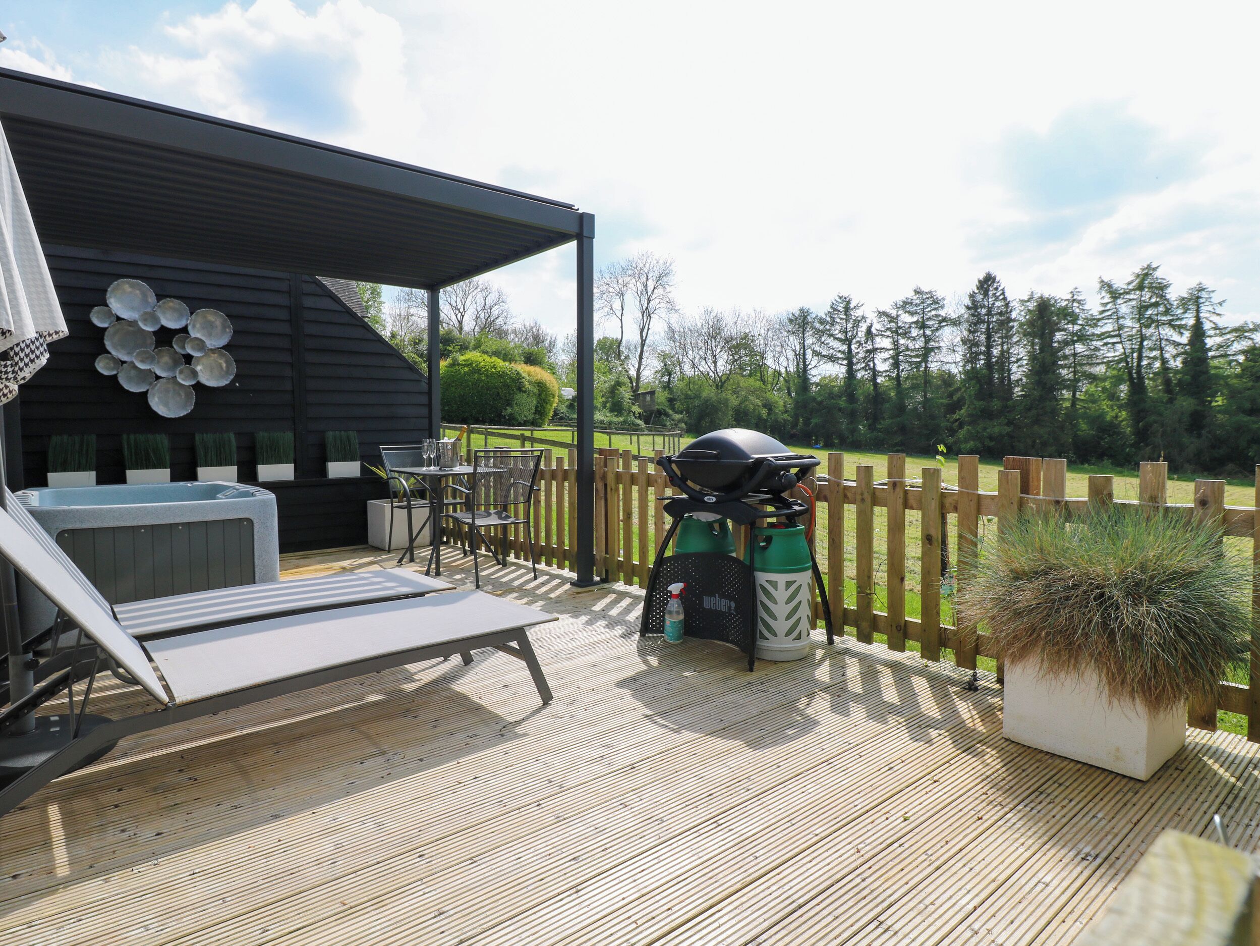 Une terrasse avec un barbecue, des sièges d’extérieur et un jacuzzi.