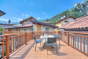 A terrace with a table and chairs, a wooden railing, and a mountainous backdrop. - Arco Rocks Apartments (Arco)