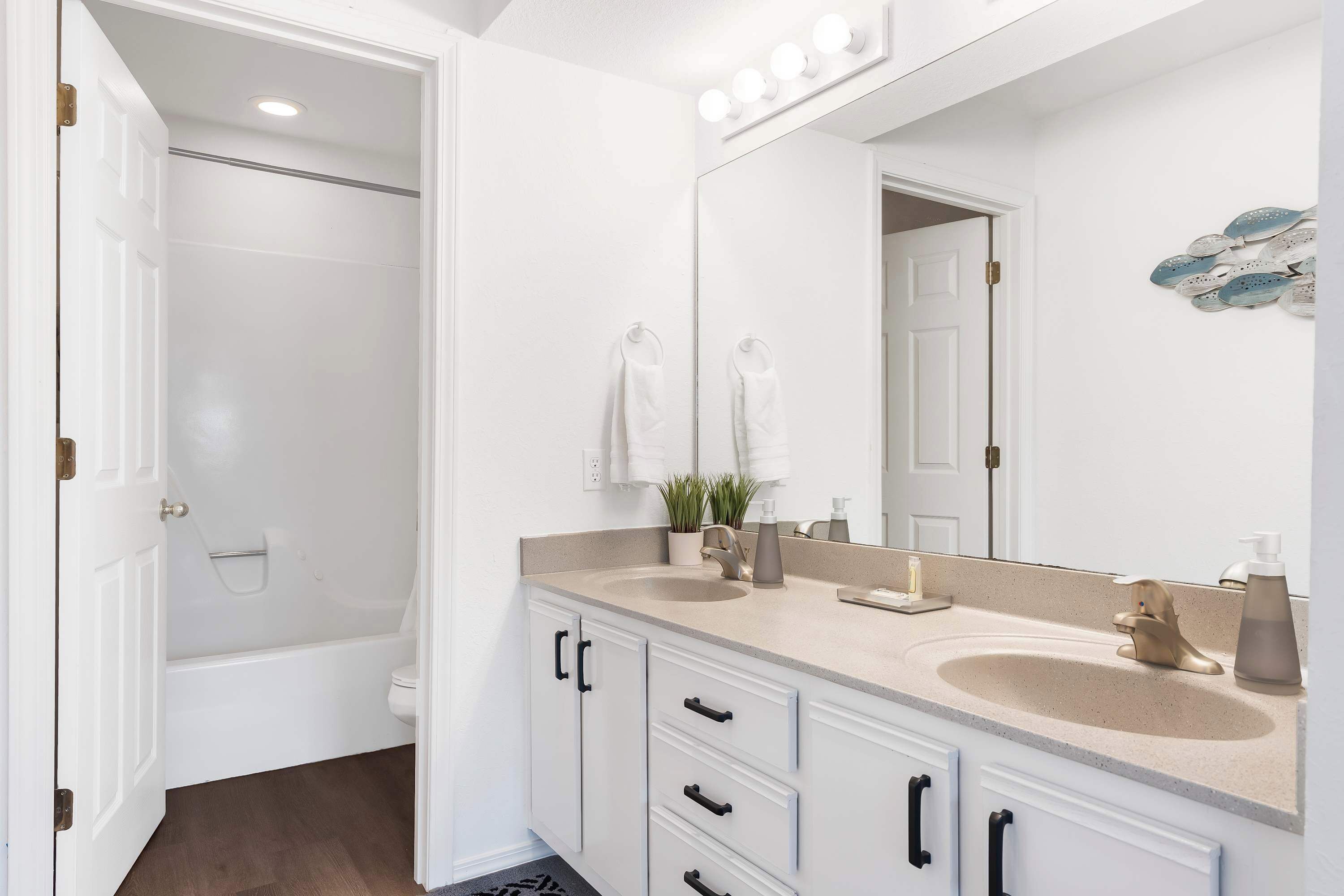 Une salle de bain avec deux lavabos, un grand miroir et une douche.