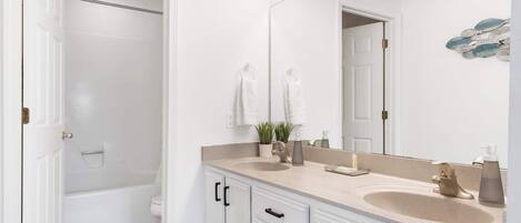 Une salle de bain avec deux lavabos, un grand miroir et une douche.