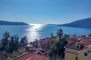 A coastal town with terracotta-roofed buildings, a clear blue sea, and a distant shoreline. - Pool Villa Luxoria Trebesin (Herceg Novi)