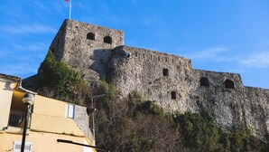 A historic stone fortress with a flag on top, a street lamp, and a building with shutters in the foreground. - Pool Villa Luxoria Trebesin (Herceg Novi)