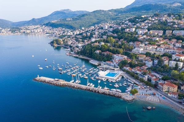 An aerial view of a coastal town with a marina, buildings, and mountains in the background. - Pool Villa Luxoria Trebesin (Herceg Novi)