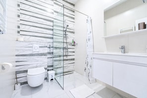 A modern bathroom with a glass shower enclosure, a toilet, and a vanity with a mirror. - Pool Villa Luxoria Trebesin (Herceg Novi)