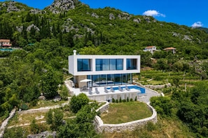 A modern two-story house with a swimming pool, surrounded by greenery and mountains. - Pool Villa Luxoria Trebesin (Herceg Novi)