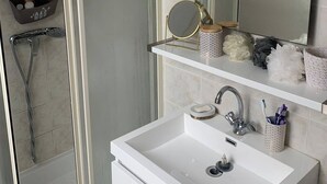 Ein Badezimmer mit Dusche, Waschbecken und Spiegel.
