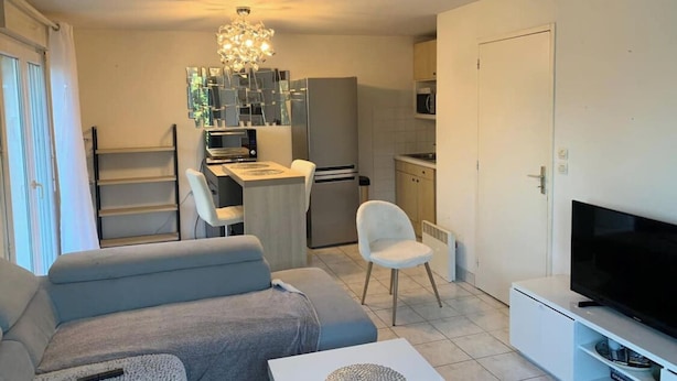 Ein modernes Wohnzimmer mit einer Couch, einem Fernseher und einem Essbereich mit Tisch und Stühlen.