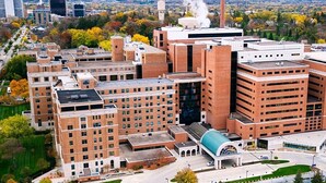 A multi-story building with a central atrium, surrounded by smaller buildings and a parking area.