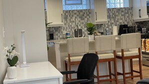 A modern kitchen with white cabinets, a tiled backsplash, and a dining area with a white table and chairs.