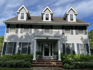 Two-story house with a central entrance, gabled roof, and balcony.