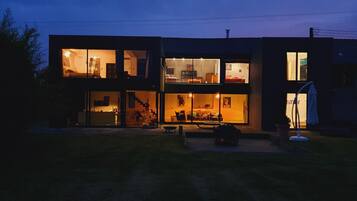Una casa moderna de dos pisos con ventanas amplias y un área de cocina visible.