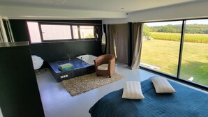 A bedroom with a large window, a bed, a small table, and a chair. - VILLA COMBINES MODERNITY AND STONES. IDEAL FOR FAMILY OR WORK (LIFFRE)