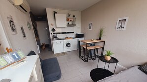 A compact living space with a kitchenette, a sofa, a small table, and a dog. - Lovely studio overlooking the Alberts at the port, with the sea in front (Saint-Cyprien)