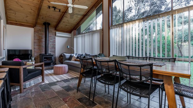 Una sala de estar acogedora con chimenea, televisor y comedor con sillas y mesa.