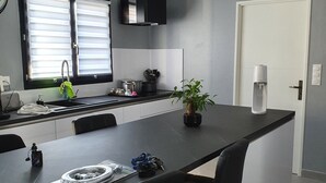 A modern kitchen with a central island, black bar stools, and a potted plant. - VILLA WITH JACUZZI (cers)