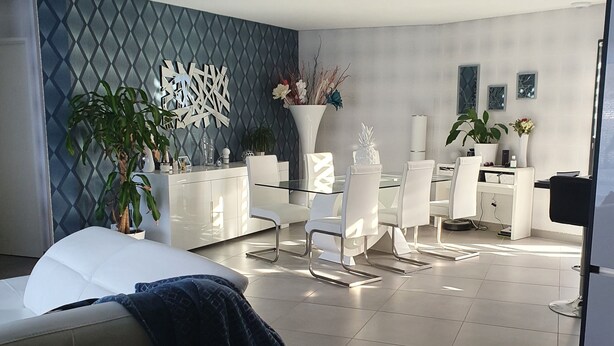 A modern hotel room with a bed, a seating area with chairs, a white dresser, and decorative plants. - VILLA WITH JACUZZI (cers)