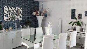 A modern dining area with a glass table, white chairs, and a decorative wall. - VILLA WITH JACUZZI (cers)