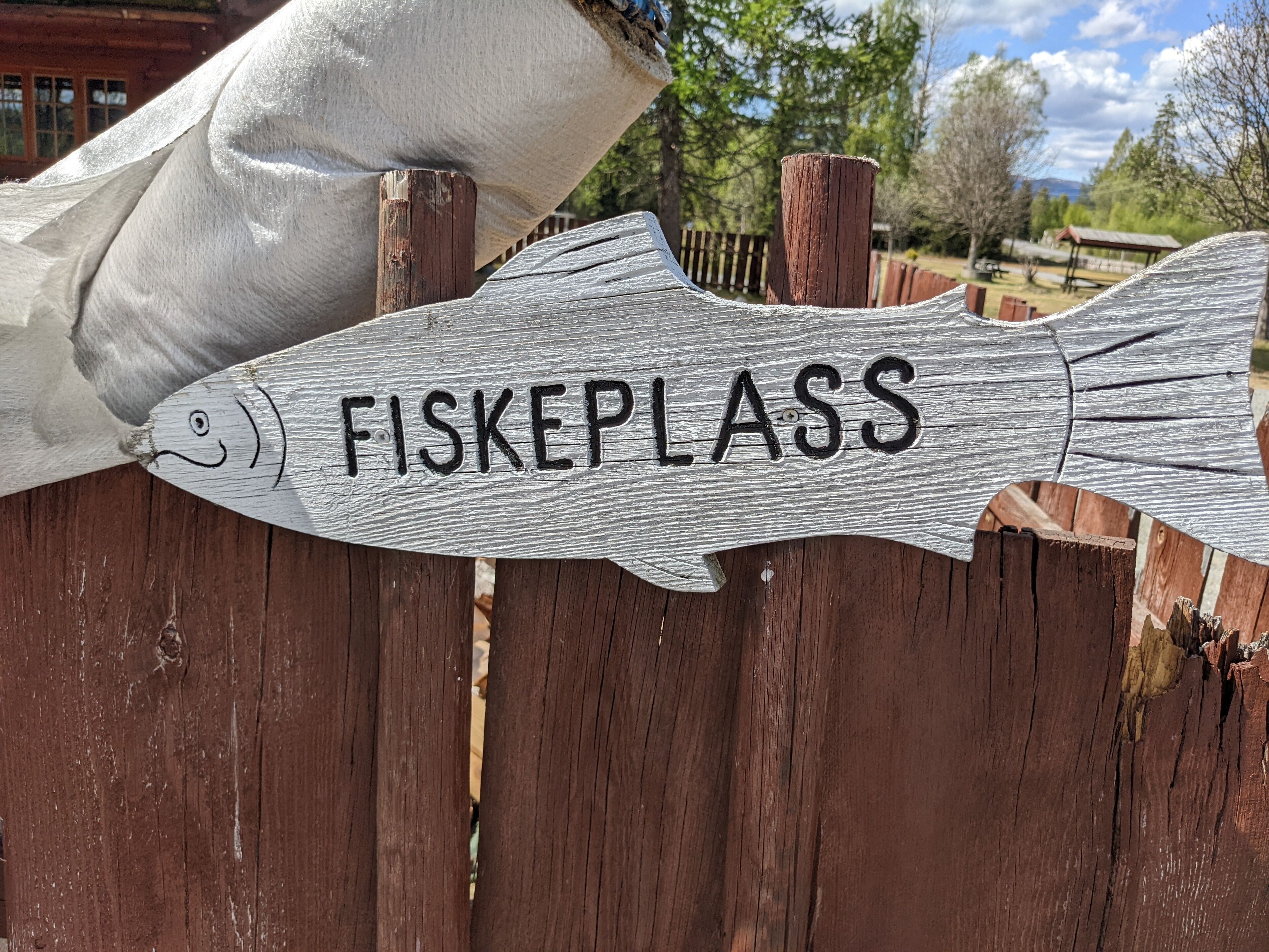 A wooden sign with the word "FISKEPLASS" on it.