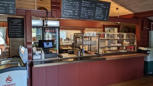 A restaurant interior with a menu board, a cash register, and a display case. - Neset Skydsstasjon (Flesberg)
