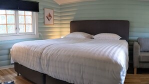 A bedroom with a bed, a window, and a chair. - Neset Skydsstasjon (Flesberg)