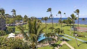 Vista de um resort com piscina, quadras de tênis e palmeiras.