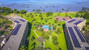 Um hotel com piscina no terraço, rodeado por palmeiras e painéis solares.