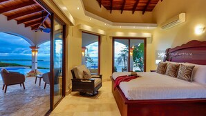 Een slaapkamer met een groot bed, een stoel en uitzicht op de oceaan.