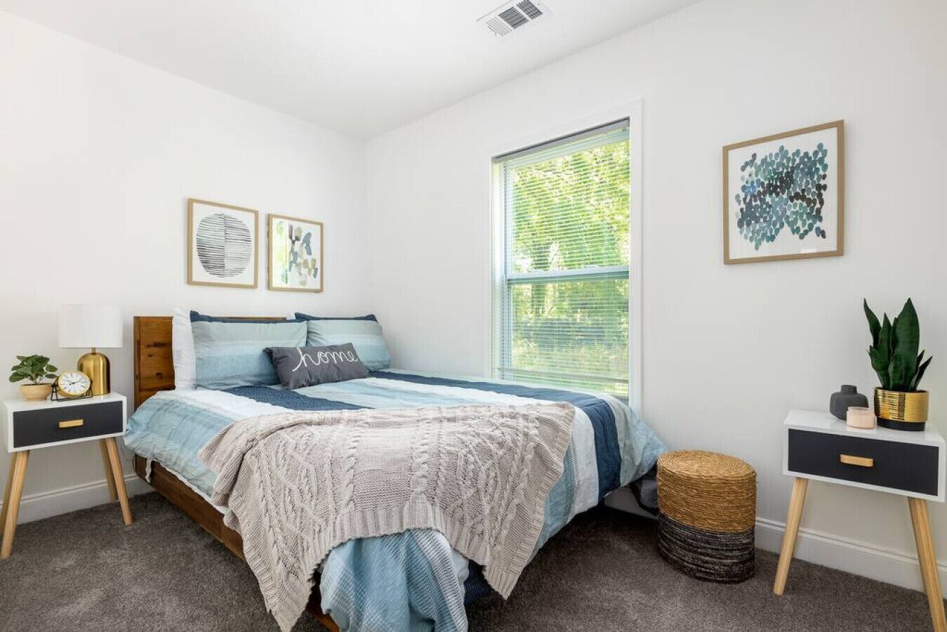 Ein Schlafzimmer mit Bett, Nachttischen, einem Fenster und Wandbildern.