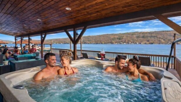 A hot tub area with a wooden deck and a view of a lake. - Lake Therapy On Keuka | Lakefront | FLX | Hot Tub (Branchport)