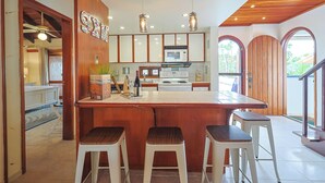 Una cocina con una isla de madera, taburetes de bar, un microondas y luces colgantes.