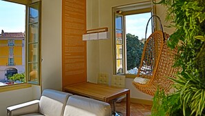 Una habitació amb taula de fusta, dues cadires, una cadira penjant i un cartell informatiu gran.