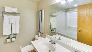 A bathroom with a sink, mirror, and toilet. There are towels on a rack and a painting on the wall. - Modern Huge Home! 11,500 sq. ft! Family Reunions or Big Group! Perfect Location  (Garden City)