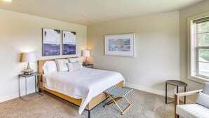 A bedroom with a bed, two bedside tables with lamps, a chair, and artwork on the walls. - Modern Huge Home! 11,500 sq. ft! Family Reunions or Big Group! Perfect Location  (Garden City)