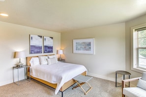 A bedroom with a bed, two bedside tables with lamps, a chair, and artwork on the walls.