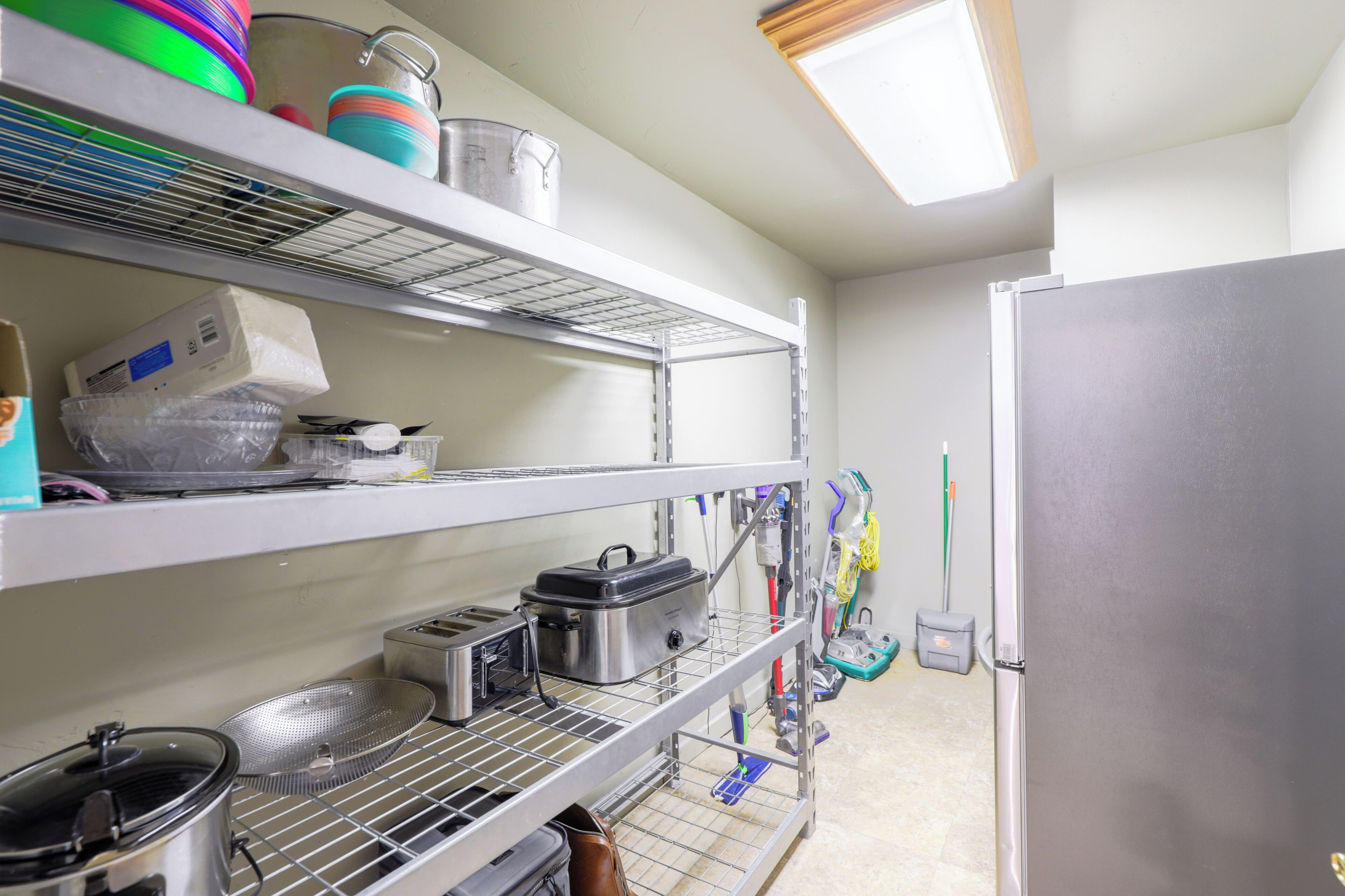 A kitchen with stainless steel shelves, a refrigerator, and various kitchen utensils.