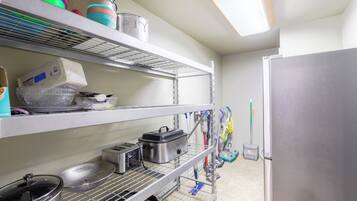 A kitchen with stainless steel shelves, a refrigerator, and various kitchen utensils.
