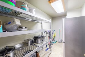 A kitchen with stainless steel shelves, a refrigerator, and various kitchen utensils.