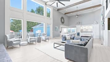 A spacious living area with a large gray sofa, a dining table, and a kitchen in the background.