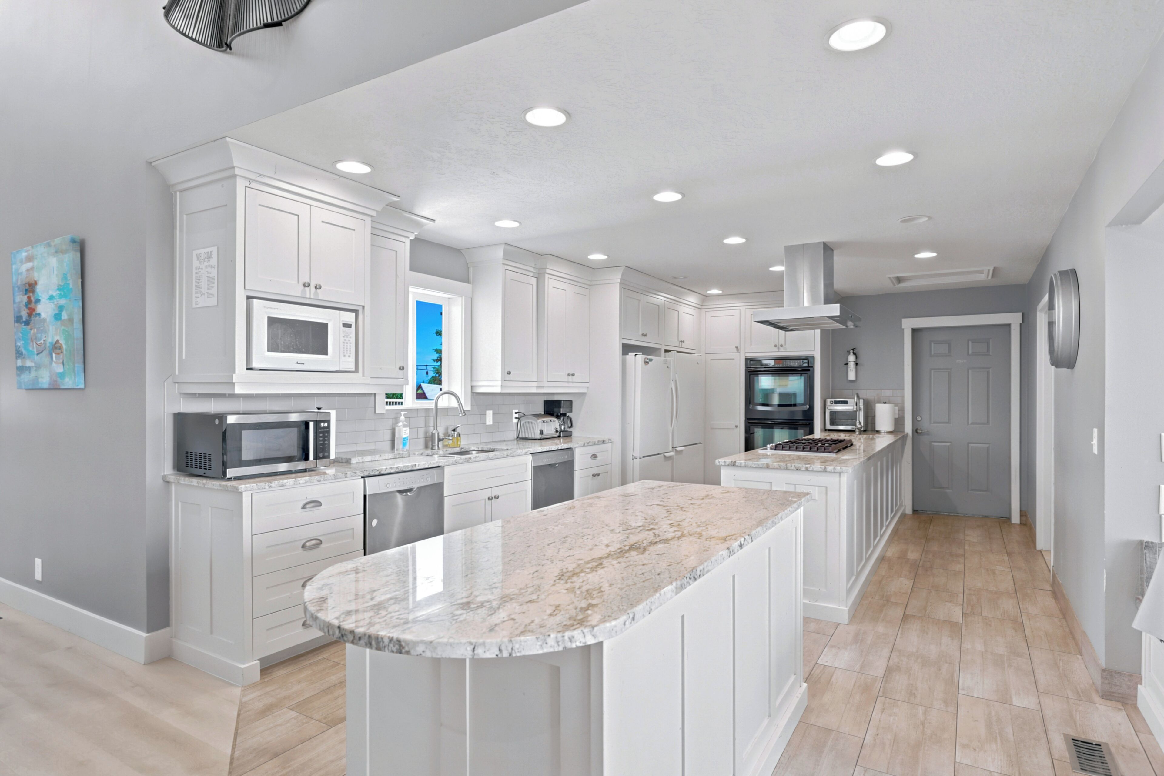 A modern kitchen with white cabinetry, a central island, and built-in appliances.