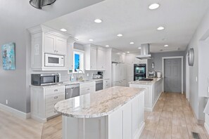 Une cuisine moderne avec des meubles blancs, un îlot central et des appareils électroménagers intégrés.