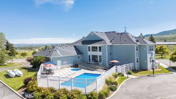 A large two-story house with a swimming pool, a covered patio, and a fenced backyard.