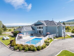 Ein großes, zweistöckiges Haus mit Swimmingpool, überdachter Terrasse und umzäunter Garten.