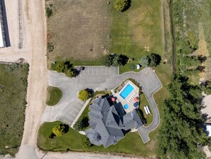 Ovenudblik over en ejendom med swimmingpool, parkeringsområde og grøn bevoksning.