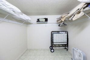 A laundry room with shelves for hanging clothes, a cart for folding laundry, and a fan on the floor.